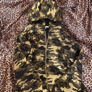 Guldig kamo tröja - Sjukt cool, fint skick förutom dragkedjan som inte går att stänga kan säkert fixas på nått sätt, guldig och svart kamouflage lite bape hoddie doop köpt på second för cirka ett år sedan, liten i storleken men sjukt snygg