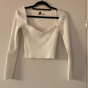 Vit ribbad topp från Divided - Säljer en superfin vit ribbad topp från Divided/H&M. Den har en snygg v-ringning och långa ärmar, perfekt för både vardag och fest. Toppen är croppad och sitter inte så tight, vilket ger en stilren look. Passar perfekt till jeans eller kjol! Hör gärna av er vid frågor eller fler bilder💕