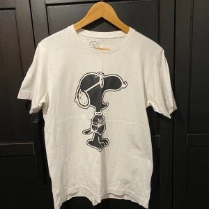 Vit KAWS x Peanuts t-shirt från Uniqlo - Säljer en vit t-shirt från Uniqlo  KAWS x Peanuts .           Size: Small.                                                                                Väl använd lite slitet tryck men bra i tyget.                         Flaw (se sista bilden) 2 fläckar inget som syns jättetydligt