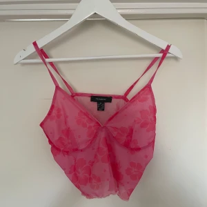 Rosa blommig topp från Primark - Säljer en superfin rosa topp från Primark. Den är axelbandslös och har ett blommigt mönster som ger en somrig känsla. Perfekt för varma dagar eller en festlig kväll. Toppen är i ett lätt och luftigt material.