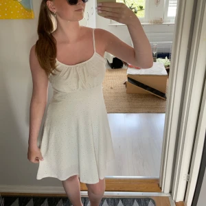 Vit klänning från Shein - Säljer en superfin vit klänning från Shein. Den är ärmlös med smala axelband (som går att justera) och har en söt, luftig passform. Perfekt för sommardagar eller en festlig kväll. Klänningen är i nyskick och har ett diskret mönster som ger den lite extra stil. Passar perfekt för en avslappnad men ändå chic look!