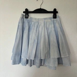 Volangkjol  - Volangkjol från weekday i blå/vit färg, tie dye tyg. Midjan är sträcker sig från 33 - 38 cm då det är resår. Två lager volanger och kjolen är ganska puffig. Knappt använd.  Storlek 34 på lappen, 100% bomull.