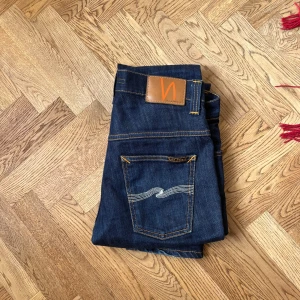 Mörkblå jeans från Nudie Jeans - Säljer ett par snygga mörkblå jeans från Nudie Jeans. De har en klassisk femficksdesign, modellen är Thin Finn. Dom är också dry så dom är otvättade från fabrik och får en sjuk fade när man använder dom, Nästan oanvända eftersom dom är för små