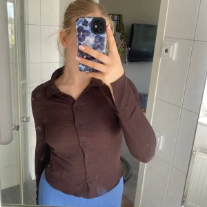 Långärmad tröja - Brun långärmad tröja med knappar på framsidan och slitsar vid handlederna. Från SHEIN, använda 1 gång. 