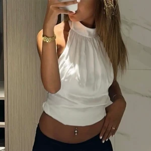 Vit ärmlös topp med knytband - Säljer en superfin vit topp som är ärmlös och har en hög hals. Toppen har snygga knytband i ryggen som ger en öppen rygg-look. Perfekt för fester eller en utekväll!🥰