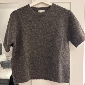 Kortärmad stickad - Säljer en mysig grå/brun stickad tröja med korta ärmar. Perfekt för kyliga dagar och enkel att matcha med olika outfits. Tröjan har en klassisk rund hals och en bekväm passform. Storlek: 158/164