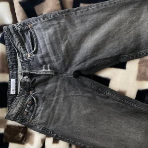 Grå jeans från Zara - Snygga grå jeans från Zara med en klassisk femficksdesign. De har en rak passform och är perfekta för en avslappnad stil. Jeansen har en knappgylf och är tillverkade i ett slitstarkt material.