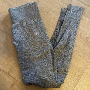 Grå leggings från ICANIWILL - Snygga grå leggings från ICANIWILL med ribbad midja och ventilerande meshdetaljer längs benen. De har en tight passform som ger bra stöd. Av någon anledning har jag klippt av lappen på insidan men skulle säga det är som en XS/S i storlek