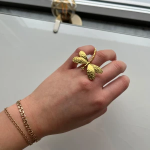 Guldfärgad ring med trollslända - Unik guldfärgad ring formad som en trollslända. Ringen har detaljerade vingar och en elegant design som fångar ljuset vackert. Perfekt för att lägga till en touch av naturinspirerad stil till din look.