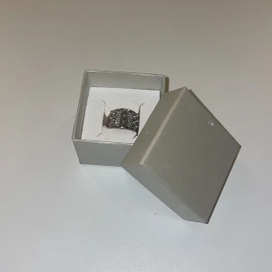 Silverfärgad ring med glittriga detaljer - Elegant silverfärgad ring med glittriga detaljer som ger en lyxig känsla. Perfekt för att addera lite extra bling till din outfit. Ringen har en bred design som gör den till ett iögonfallande smycke.