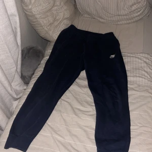 Svarta mjukisbyxor från Nike - Säljer ett par svarta mjukisbyxor från Nike. Byxorna har en elastisk midja och ribbade muddar vid bensluten. Perfekta för en avslappnad stil.