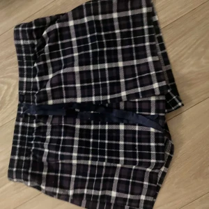 Rutig shorts med snörning - Snygga rutig shorts i mörka toner med snörning framtill. Perfekta för en avslappnad stil. De har en bekväm passform och är gjorda i ett mjukt material.