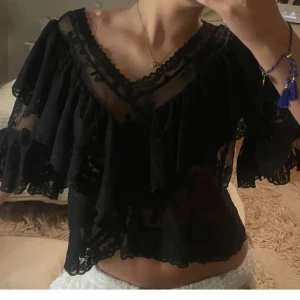 Svart spetsblus med volangdetaljer - Säljer en elegant svart blus i spets med volangdetaljer. Blusen har ingen lapp kvar och därför vet jag tyvärr ej märket. 💞