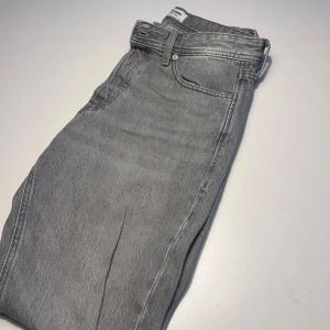 Grå jeans från Jack & Jones - Snygga grå jeans från Jack & Jones med en relaxed fit. De har en klassisk femficksdesign och en knappgylf. Perfekta för en avslappnad stil.