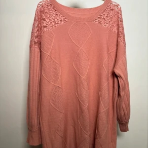 Rosa stickad tröja med spetsdetaljer - Säljer en söt rosa stickad tröja med vackra spetsdetaljer på axlarna. Tröjan har ett unikt mönster framtill och långa ärmar. Perfekt för en mysig dag.