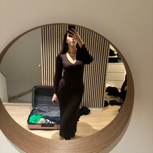 Brun ribbad långklänning - Snygg brun ribbad långklänning med v-ringning och långa ärmar. Perfekt för en stilren look.