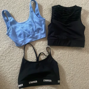 Tre sportiga toppar från Stronger - Säljer tre sportiga toppar från Stronger. En ljusblå ribbad topp med breda axelband, en svart topp med ett diskret mönster och en svart topp med smala axelband och logga vid nederkanten. Perfekta för träning eller en aktiv dag. M och s.