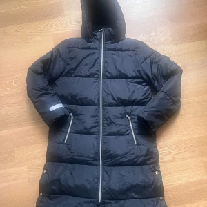 Lång Dunjacka strl 164 - Jättefint skick!  Avtagbar luva, dragkedja på fickorna. 