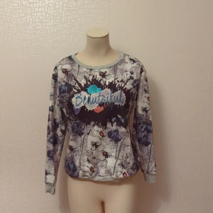 Blommig tröja med text från CRC - Säljer en superfin blommig tröja från CRC i storlek M. Tröjan har ett coolt tryck med texten 'Beautiful' i mitten och är täckt av ett vackert blommönster i blått och vitt. Den är långärmad och perfekt för både vår och höst. Materialet känns mjukt och skönt mot huden. Perfekt för en avslappnad dag eller en mysig fika med vänner!