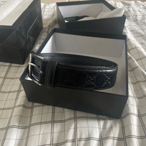 Svart Gucci skärp - Använd flertal gånger. Själva metallbiten som man spänner fast bältet med är lite löst, men ingenting som syns eller förstör användningen av själva bältet. Två extra hål har även gjorts för ett tag sen då skärpet va för stort för mig. Kartong och pås