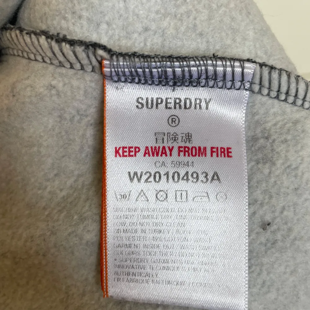 Säljer en supersnygg grå collegetröja från Superdry. Den har en klassisk rund hals och är i ett melerat grått mönster med Superdry:s vita logga på bröstet. Använd en gång - perfekt skick!. Tröjor & Koftor.