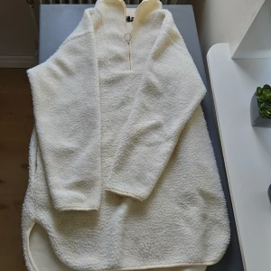 Vit fleece tröja från Pieces - Mysig och varm vit fleece tröja som slutar strax under rumpan från Pieces. Perfekt för kyliga dagar med sin mjuka och fluffiga textur. Tröjan har en halv dragkedja framtill och långa ärmar. Den är i bra skick och redo att hålla dig varm hela vintern!