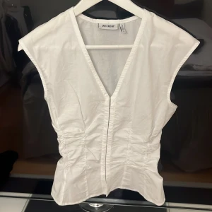 Vit blus  - En ärmlös blus. V-ringning och stängs med hyska och hake fram. Aldrig använd. Fint skick🫶🏼