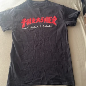Svart Thrasher T-Shirt - Detta är en svart thrasher t-shirt i storlek S för barn mellan 12-14. Den är sällan använd och har ett riktig snygg vit svart tryck där de står trasher.