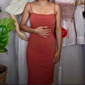 Rostfärgad ärmlös klänning - Snygg rostfärgad klänning i tight passform. Den är ärmlös och perfekt för både vardag och fest. Materialet ser ut att vara mjukt och stretchigt, vilket gör den bekväm att bära. En stilren och enkel design som kan matchas med olika accessoarer.