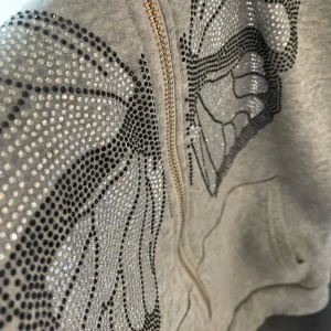 Grå hoodie med fjärilsdetaljer från Shein - Säljer en snygg grå hoodie från Shein med glittriga fjärilsdetaljer. Den har en dragkedja framtill och en mysig huva. Perfekt för en avslappnad stil med lite extra bling! 🦋✨Även mycket varm tröja!