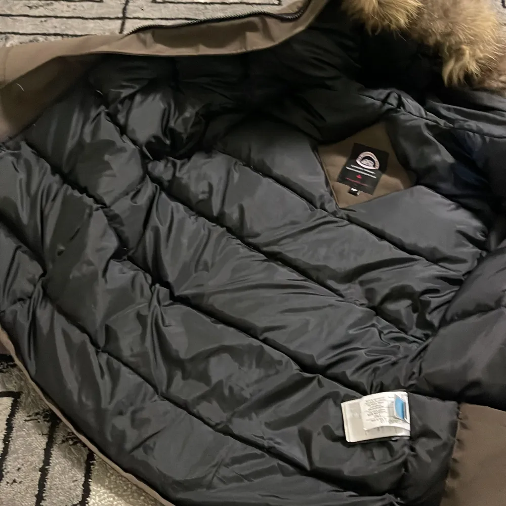 Säljer en brun parkajacka från Canada Goose i mycket bra skick. Jackan har en varm pälsfodrad huva och dragkedja med knappar. Perfekt för kalla vinterdagar. Den är långärmad och quiltad för extra värme. Passar både höst och vinter.. Jackor.