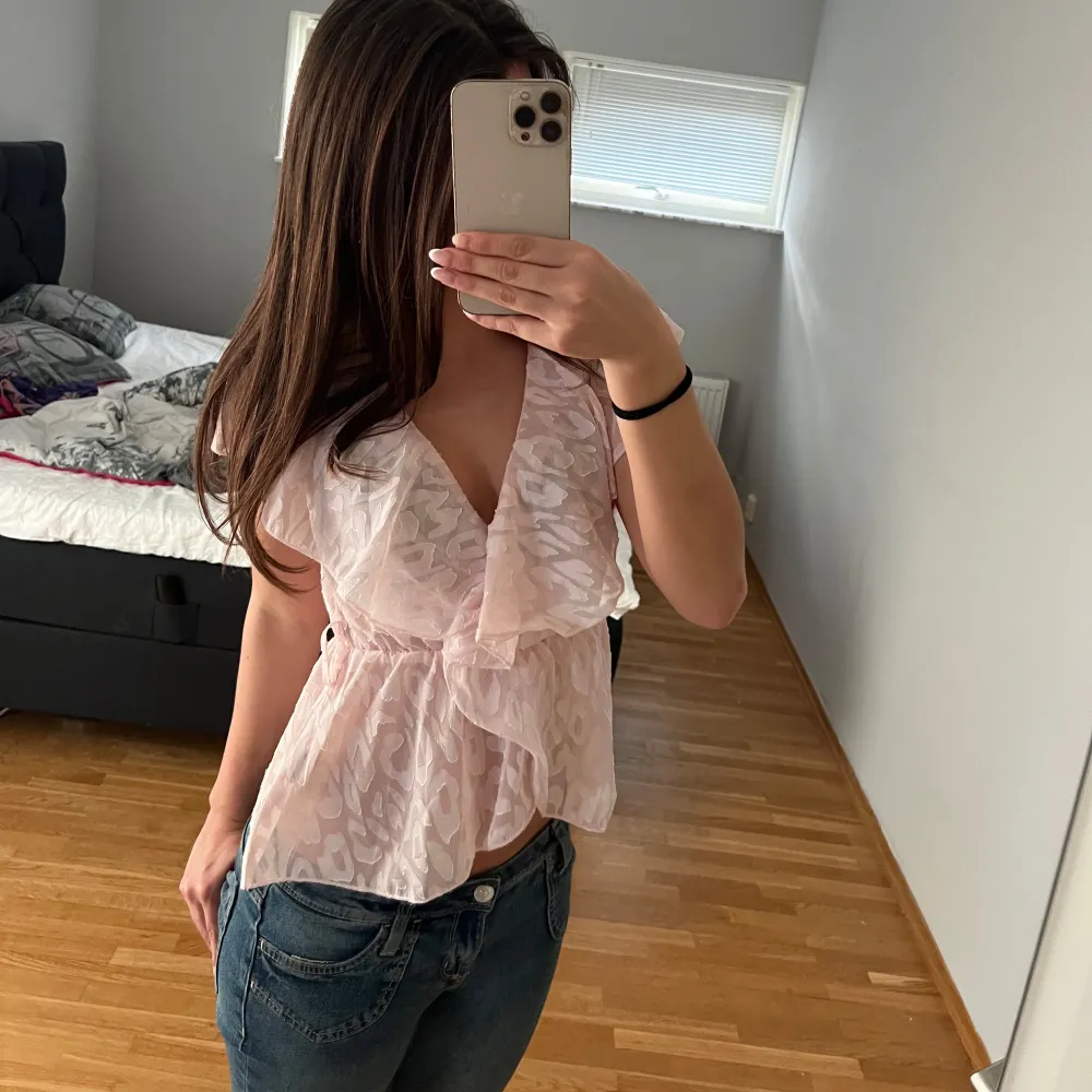 Säljer en söt rosa blus med blommigt mönster. Den har en v-ringad design och volanger som är perfekt för en liten finare look. Perfekt för vår och sommar! Passar bra till både jeans och kjol.. Toppar.