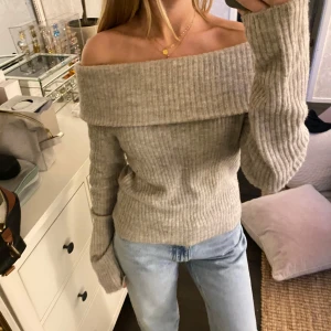 Beige offshoulder tröja  - Säljer en trendig superfin beige offshoulder tröja från H&M. Den är stickad och har en ribbad design som ger en snygg look. Perfekt för hösten nu och den kalla vintern. Passar fint med kjol, jeans och kostymbyxor! 