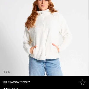 Vit pilejacka 'Cosy' - Mysig vit pilejacka med dragkedja framtill. Perfekt för kyliga dagar när du vill hålla dig varm och bekväm. Jackan har en avslappnad passform och är supermjuk att ha på sig. Perfekt för både vardag och chilliga stunder.