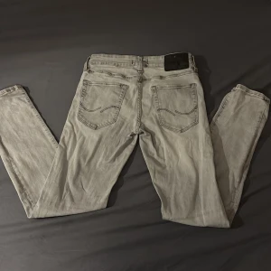 Jack&Jones Slim fit glenn jeans - Säljer ett par grå slimfit jeansbyxor, modell glenn, med storlek 28/30 (28 i höften och 30 i längden) i bra skick.  De har en klassisk femficksdesign med knappar och dragkedja framtill. Perfekta för både vardag och fest! Vid frågor eller funderingar, skriv till mig😃
