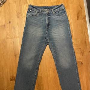 Säljer ett par blå jeans från H&M i loose fit med justerbar midja. De har en klassisk femficksdesign och är i bra skick med en liten slitagefläck på baksidan. Perfekta för en avslappnad stil!