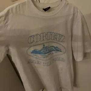 Säljer en vit t-shirt från Cortez i storlek medium. Den har ett coolt blått tryck med texten 'Cortez Rules the World' och en bild av ett skepp. Perfekt för en avslappnad stil!