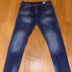 Blå jeans från Dsquared2 - Säljer ett par snygga blå jeans från Dsquared2 i storlek 42. De har en cool slitningseffekt och klassisk femficksdesign. Perfekta för både vardag och fest! 🕺
