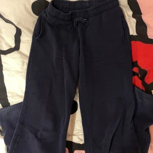 Mörkblå mjukisbyxor Ginatricot - Säljer ett par mörkblå mjukisbyxor i bra skick. De har en elastisk midja med snörning och är perfekta för en avslappnad dag hemma eller på gymmet. Byxorna har en loose passform och är gjorda av mjukt material för extra komfort. Xs.