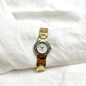 Elegant klocka i guld och silver - KAMPANJ 🥂Klockan Sigrid från märket QUARTZ är en guldklocka med vit urtavala med en unik ram.   Urnets diameter:24 mm Omkrets:16,5cm Längd:18cm 