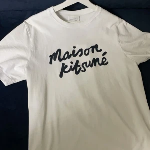 Maison Kitsuné t-shirt - Säljer en snygg vit t-shirt från Maison Kitsuné. Perfekt för en avslappnad stil och passar till alla tillfällen. Storleken är S men den passar M. Ny pris på denna t-shirten är 1500kr, tar även byten. T-shirten är i nyskick. Perfekt till sommaren! 🌞