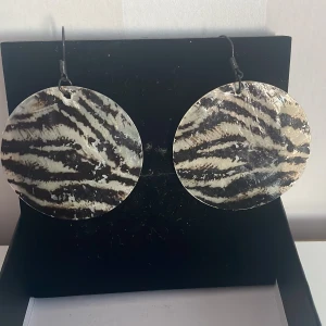 Zebramönstrade örhängen - Snygga och trendiga örhängen med zebramönster. De är runda och stora, perfekta för att ge en djärv touch till din outfit. Passar både till vardags och festliga tillfällen. Ett måste för dig som älskar djurmönster!