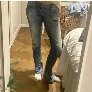 Blå jeans med slitningar - Säljer ett par snygga blå jeans med coola slitningar. De har en tight passform och är perfekta för en avslappnad stil. Jeansen är i bra skick och har en klassisk femficksdesign. Perfekta för både vardag och fest!
