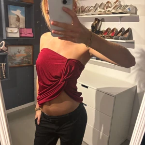 Röd axelbandslös topp - Säljer en snygg röd axelbandslös topp i sammet.