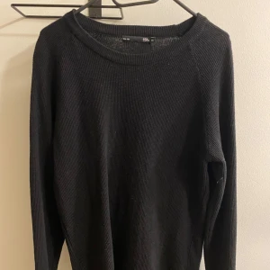 Svart stickad tröja  - Säljer en stilren svart stickad tröja. Perfekt för både höst och vinter med sin mjuka och bekväma passform. Tröjan har långa ärmar och en rund halsringning. Passar till alla tillfällen, både vardag och fest!