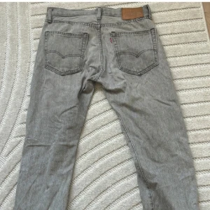 Grå Levis 551 Jeans - Säljer ett par grå Levis 551 jeans i bra skick. De har en klassisk femficksdesign och en bekväm passform. Perfekta för både vardag och avslappnade tillfällen. Storleken är 31x32 och de har en snygg vintage-look.