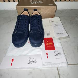 Säljer ett par snygga mörkblå sneakers från Christian Louboutin i nytt skick. Skorna är i skinn och har klassisk snörning. Perfekta för både vardag och fest! Kommer med originalförpackning och certifikat. Passa på att köpa dessa lyxiga skor! 💙