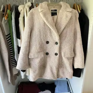 Säljer en supermysig beige teddyjacka från Pull&Bear i storlek S. Den har en dubbelknäppt design med stora knappar och två fickor fram. Perfekt för höst och vinter när du vill hålla dig varm och stilren. Jackan är i mycket bra skick och redo för nya äventyr! 🧥✨