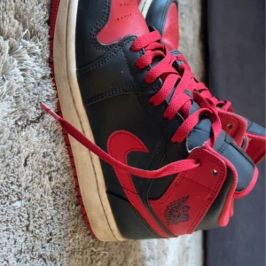 Nike Air Jordans i svart och rött - Säljer ett par klassiska Nike Air Jordans i svart och rött. Skorna har en snygg design med röd snörning och den ikoniska Air Jordan-loggan. Perfekta för både vardag och fest. De är i bra skick och redo för nya äventyr!