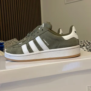 Adidas Originals Campus 00s Junior - Tänkte sälja mina nya campus i olivgrön från jd sports, då jag inte kommer ha användning för dom när jag ska till fjällen och säsonga. Supersnygga och bekväma💚köpte dom för nån månad sedan men endast använt 3 gånger.